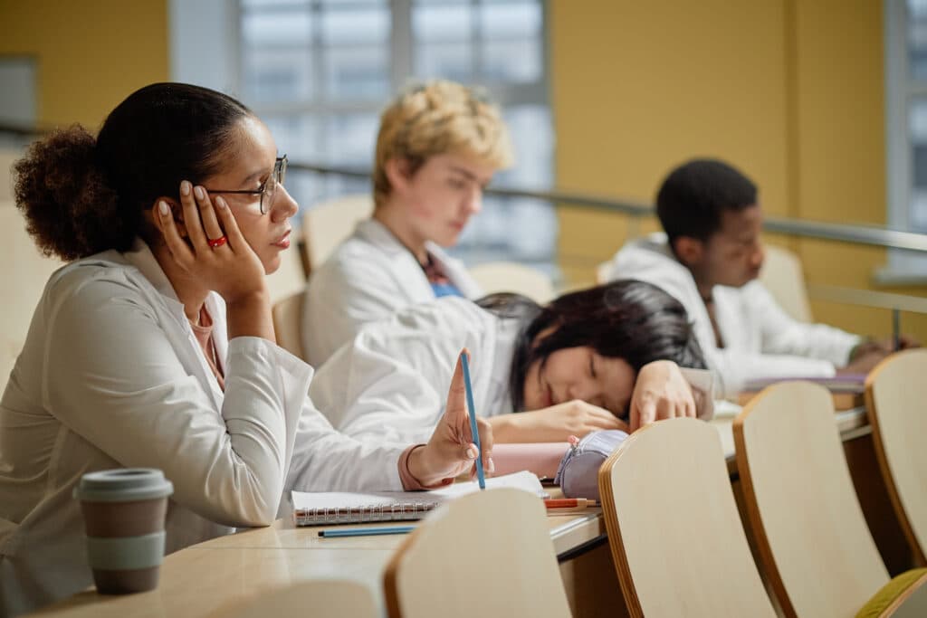 NI-BC Exam Preparation Side view portrait of young Asian medical student resting on desk in lecture hall during university class