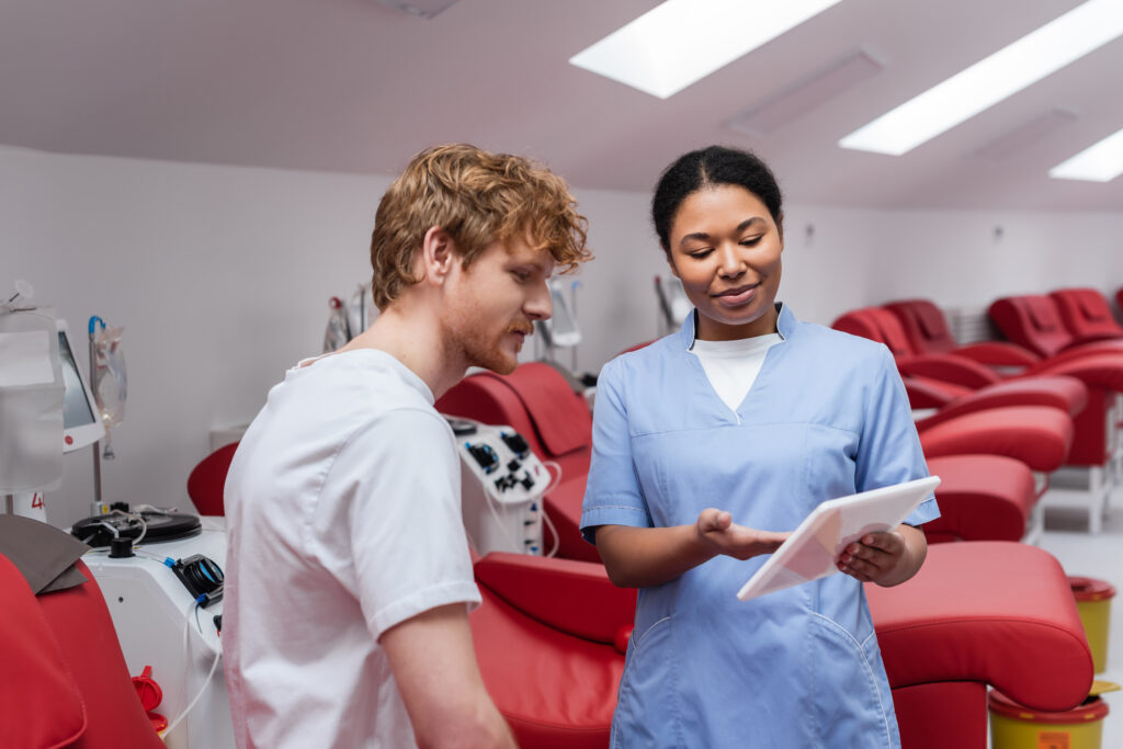 Nursing leadership professional using a digital tablet to educate a patient and support informed clinical care decisions in a modern healthcare setting.